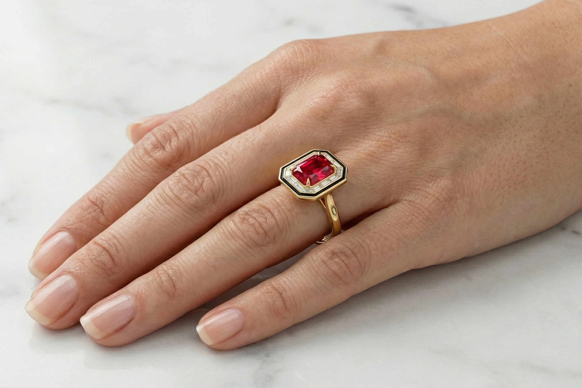 art deco Gold ring with a fancy vivid red radiant cut diamond on a hand against a white marble background